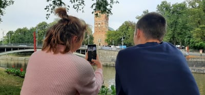 Två personer sitter med ryggen mot kameran och tar med telefonen ett foto av Åbo domkyrka.