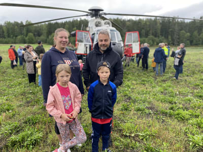 En familj med två barn framför en helikopter.