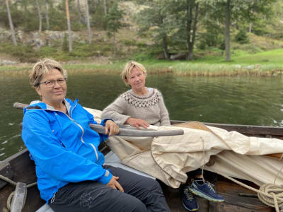 Två äldre kvinnor sin sitter i en gammal allmogebåt.