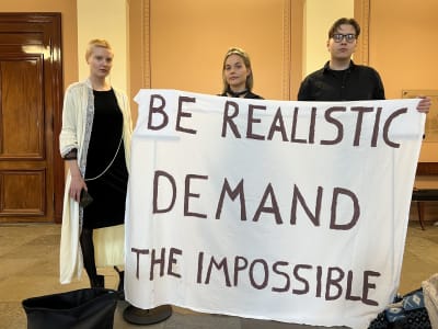 Studerande med en banderoll där det står "Be realistic, demand the impossible".