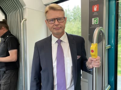 En man klädd i kostym står i en spårvagn.