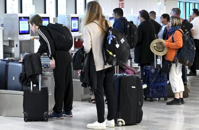 Människor med reseväskor vid incheckningen på Helsingfors-Vanda flygplats.