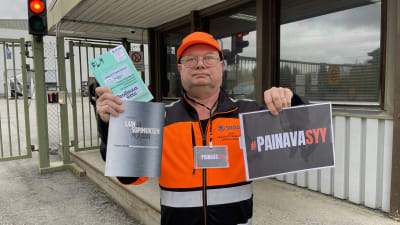 Škoda Transtechin pääluottamusmies Jouni Lämpsä pitää kädessään kahta kirjaa ja Painava syy -kylttiä.