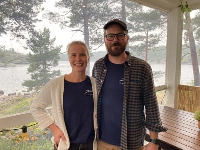 En kvinna och en man i ett kafé med havet i bakgrunden.
