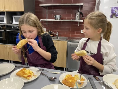 Två flickor som provsmakar mat de gjort på en kockkurs.