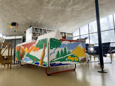 En soffa gjord i trä, där de yttre delarna har ett landskap målat i starka färger.