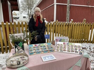 En ung kvinna som säljer örhängen på en marknad.
