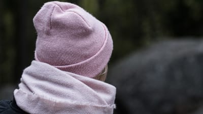 Ryggsidan av en person med vinterkläder och mössa. 