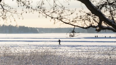 Talvinen maisema meren jäältä jossa kävelee ihmisiä.