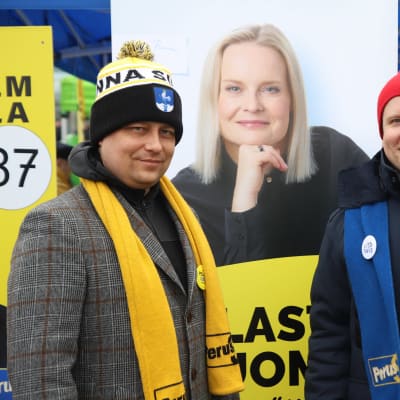 Vilhelm Junnila ja Ville Tavio poseeraavat Riikka Purran vaalijulisteen edessä.