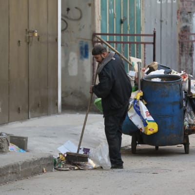 Palestinsk UNRWA-medarbetare sopar gatan i ett flyktingläger nära Nablus på Västbanken. 