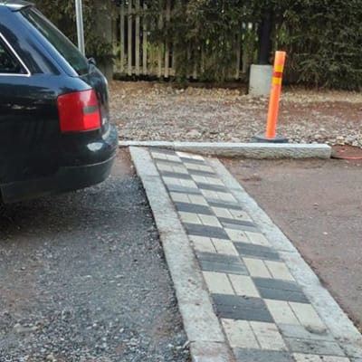 Sandväg med stenlagt farthinder, bakdel av bil som just kört över