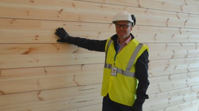 Timo Tenhunen tar med handen på en stockvägg i en ny skola