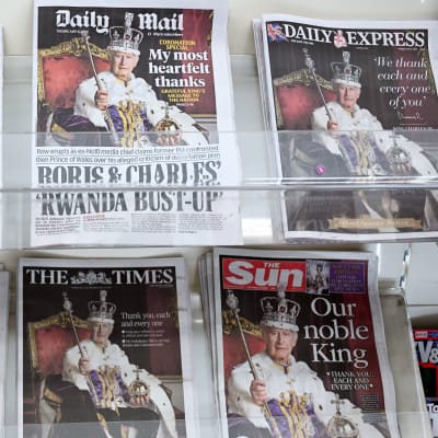 En brittisk tidningshylla där samtliga tidningar har kung Charles med krona på huvudet och spira i handen på pärmen.