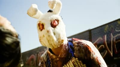 En skrämmande, kaninliknande människofigur med blodiga kläder.