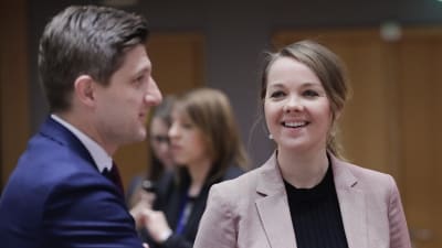Katri Kulmuni i rosa kavaj, står och pratar med någon och ser glad ut.