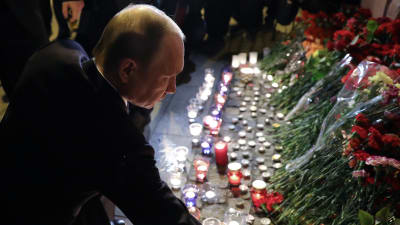 Putin lägger ner blommor utanför metrostation efter attacken i S:t Petersburg.