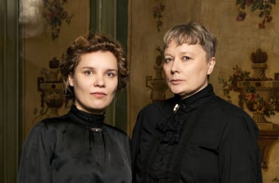 Tutkijat Nuppu Koivisto-Kaasik ja Susanna Välimäki seivovat vierekkäin mustissa asuissaan ja katsovat kameraan.