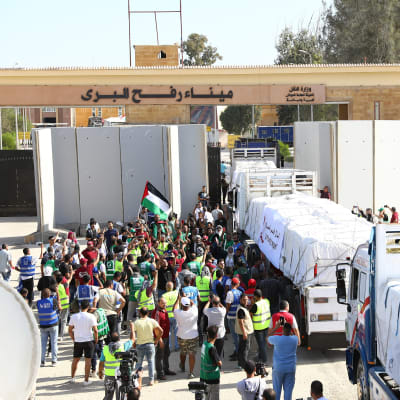 Människor och lastbilar samlade vid gränsstationen mellan Egypten och Gaza. En lastbil kör in i Gaza.