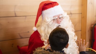 Ett barn berättar sina julklappsönskemål till julgubben.