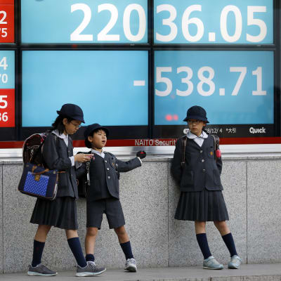 Skolbarn i Tokyo framför en skärm med börskurser i december 2018.