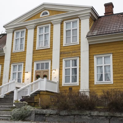 kvinna på trappa till gult hus