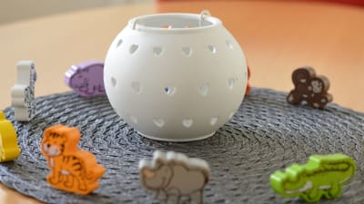 Leksaksfigurer  som föreställer djur står på ett bord, runt en vit, rund lykta