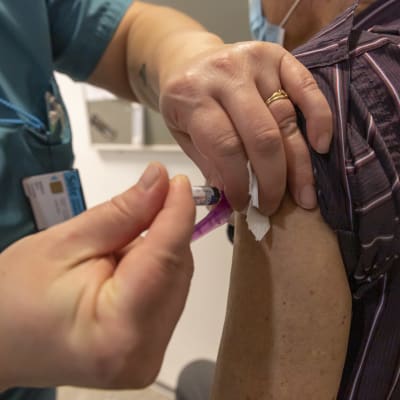 Sjukskötare injicerar influensavaccin i en arm.