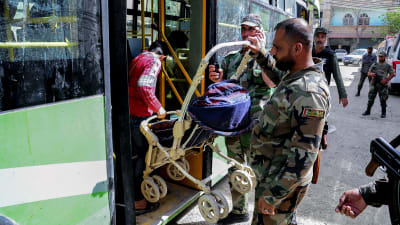 Syriska regeringssoldater hjälpte civila med att lyfta deras ägodelar i bussar som tar dem norrut, till Idlib 