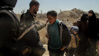 Civila får lämna Östra ghouta. En pojke med mobiltelefon i handen tillsammans med syriska regeringssoldater.