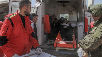 En kvinna ligger i en ambulans och får hjälpa av Röda halvmånen och internationella Röda korset.