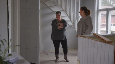 Claire Witick-Mäkelä och Åsa Björkman skrattar i ett rum med vita träväggar.