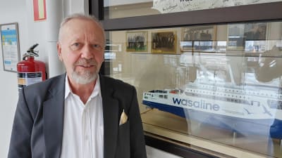 Wasalines vd Peter Ståhlberg ser mot kameran med en modell av fartyget Aurora Botnia bredvid honom. 