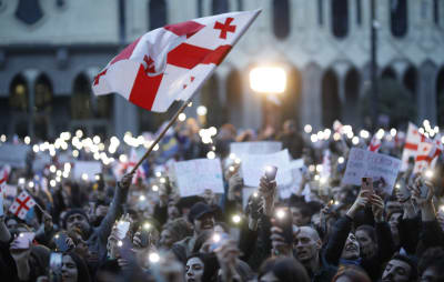 Demonstranter håller upp sina mobiltelefoner. En georgisk flagga syns i förgrunden.
