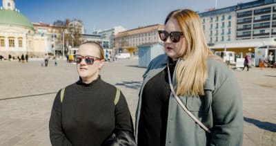 Två kvinnor med solglasögon på Åbo salutorg.