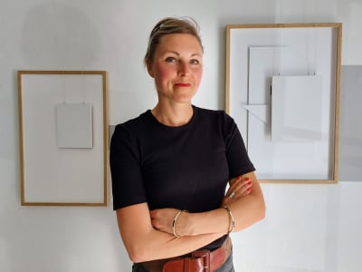 Bildkonstnären Cecilia Cissi Hultman poser framför sina tavlor.