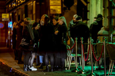 Människor som väntar på trottoaren utanför en bar
