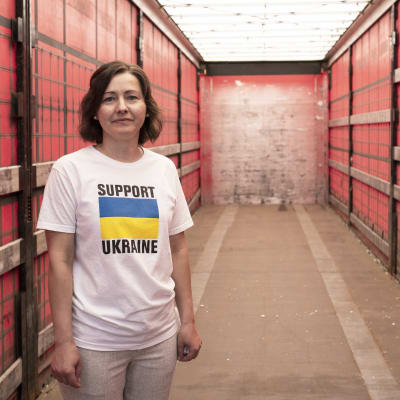 En kvinna med en Ukraina tröja står i en tom container. 