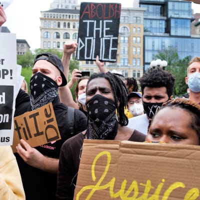 Demonstranter som protesterar mot polisbrutalitet håller i skyltar och har munskydd på sig i USA.