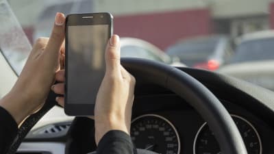 En bilförare håller en smarttelefon.
