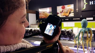 En bloggare visar sin kamera med det foto hon tagit av en bläckfisk i tyg vid fiskdisken i Åbo saluhall.