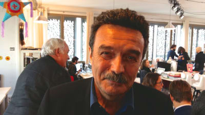 Edwy Penel har mörkt hår och mustasch, i bakgrunden ett redaktionslandskap.