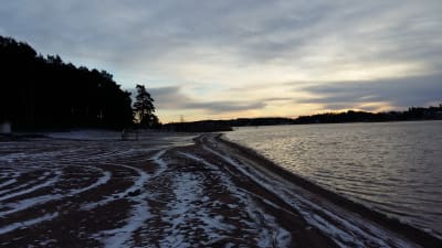 Ispois simstrand på vintern, med snö och is på stranden, men ingen is på Långvattnet.