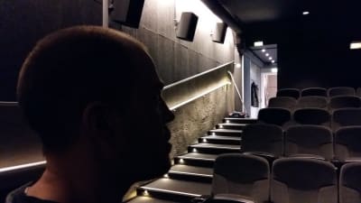 En man står i mörkret i en biosalong.