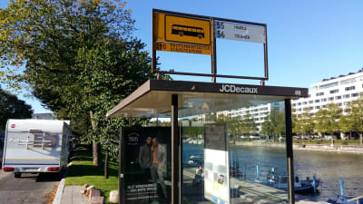 En busshållplats vid Åbo stadsteater, med reklam för Sokos.