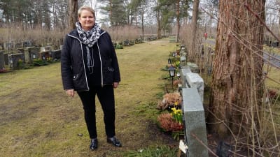 Byråchef Maria Wikström med en lutande gravsten, som har fått en gul lapp om att saken borde åtgärdas.