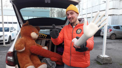 Jonathan Granbacka håller i en handen av en skyltdocka framför en fullpackad bil.