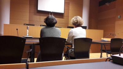 Två kvinnor fotograferade bakifrån i rättssalen.