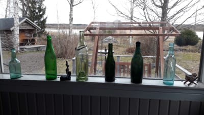 Gamla flaskor på fönsterkarm i en sommarstuga vid Djupsten i Nykarleby