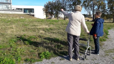 Dorrit Söderblom pekar upp mot ett bostadshus. Lisbet Tuominen står bredvid.
